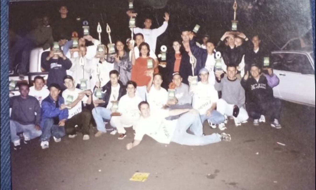 Equipe reunida com troféus em registro histórico da Nanini Som